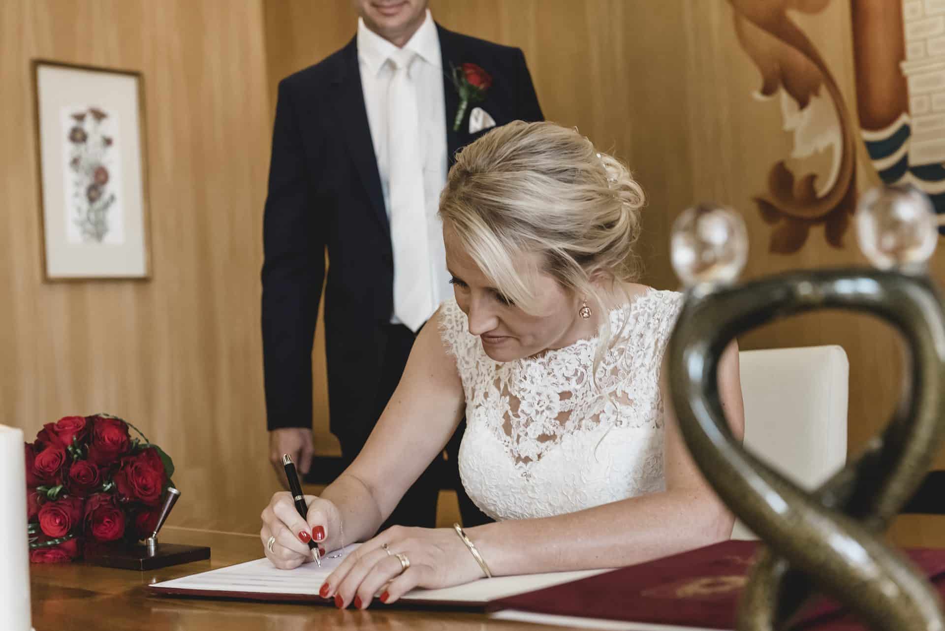 Eine Braut und ein Bräutigam unterzeichnen ihr Eheversprechen.