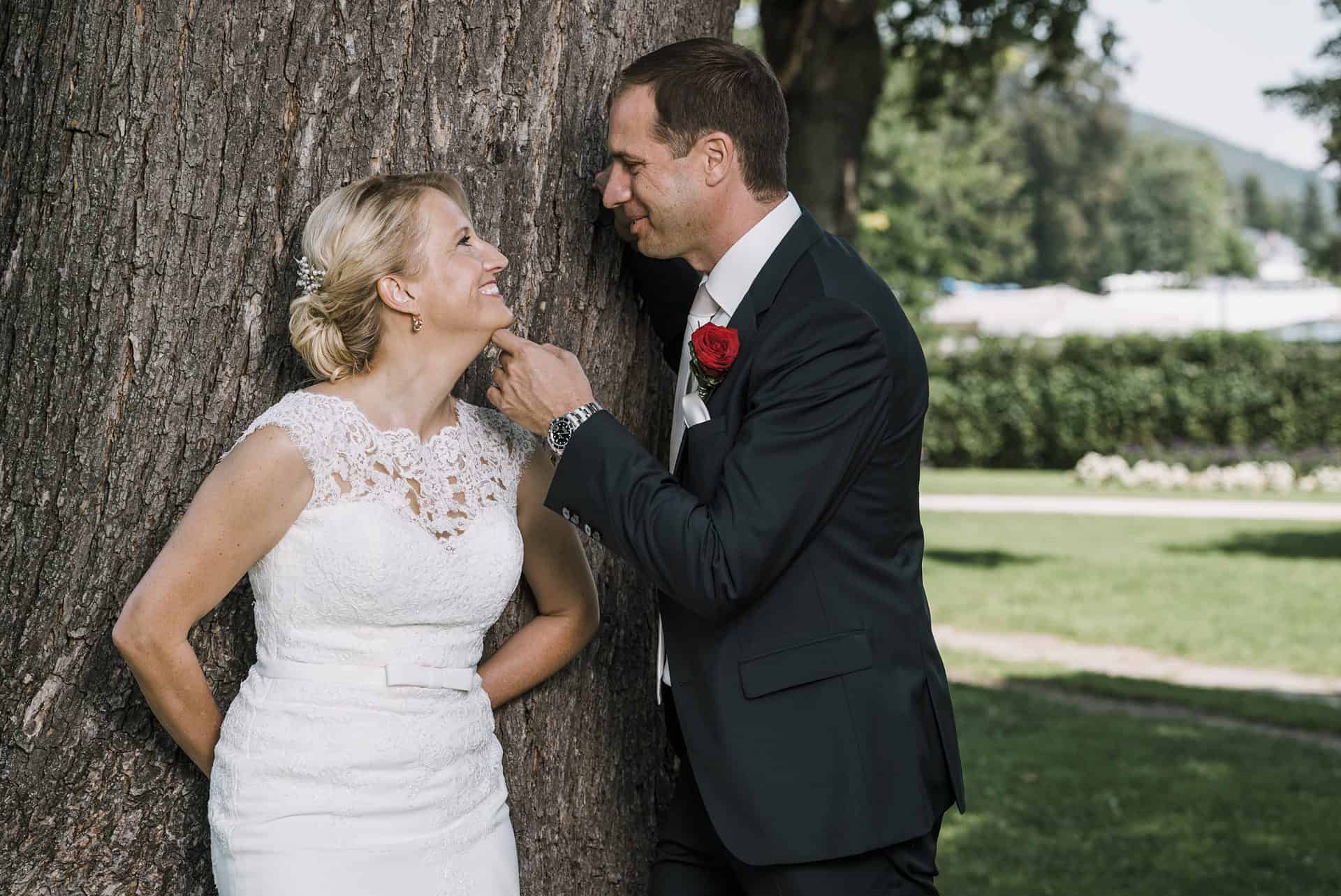 Eine Braut und ein Bräutigam lehnen sich an einen Baum.
