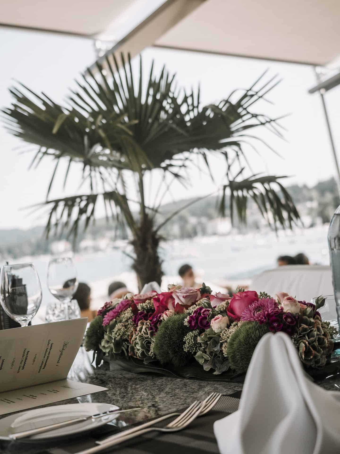 Ein gedeckter Tisch mit Blumen und einer Palme.