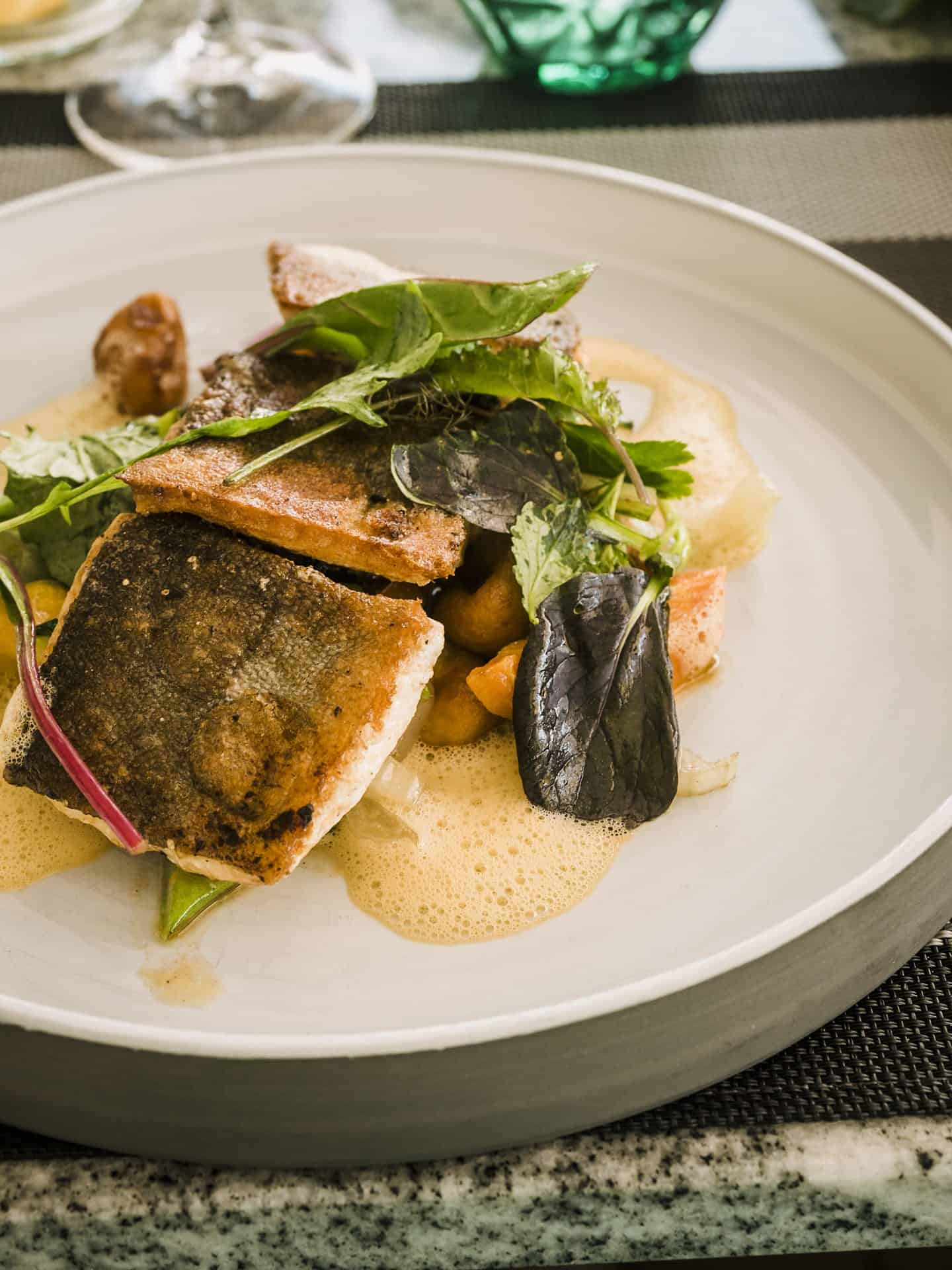 Ein Teller mit Fisch und Gemüse auf einem Tisch.