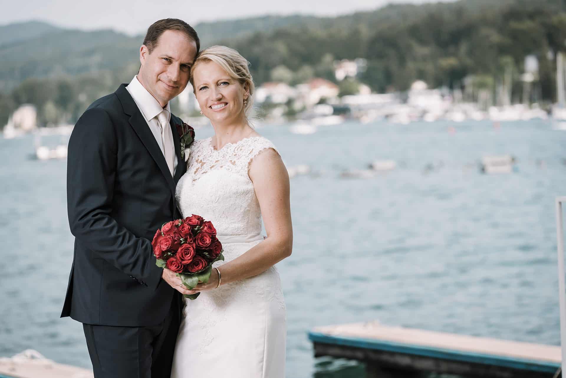 Eine Braut und ein Bräutigam posieren für ein Foto auf einem Dock.