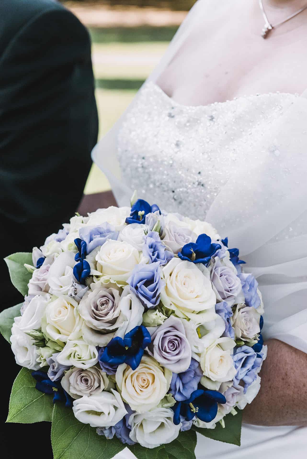 Eine Braut hält einen blau-weißen Hochzeitsstrauß.