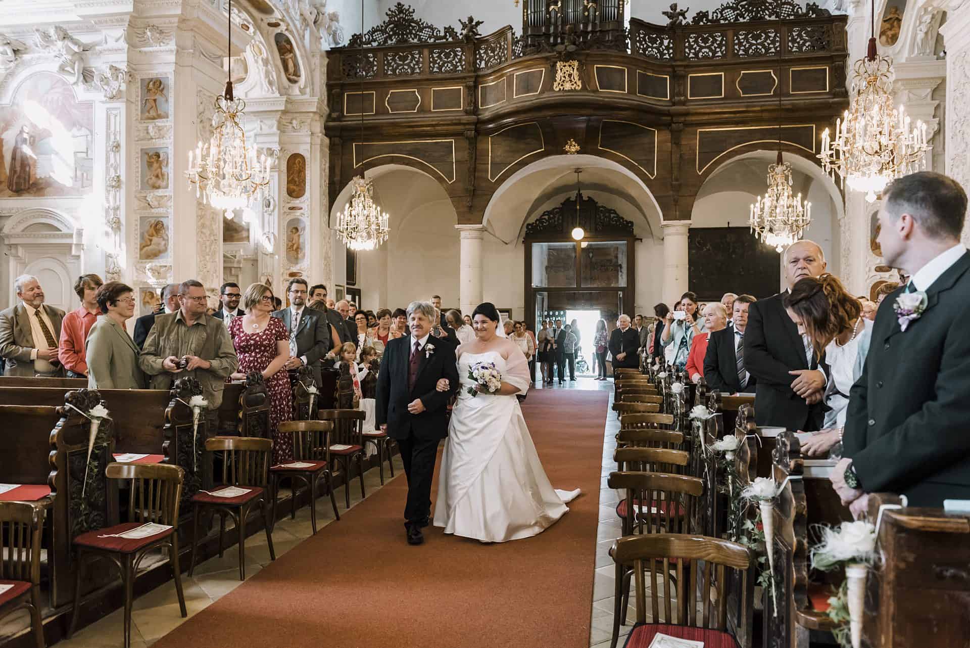 Eine Braut und ein Bräutigam gehen den Mittelgang einer Kirche entlang.