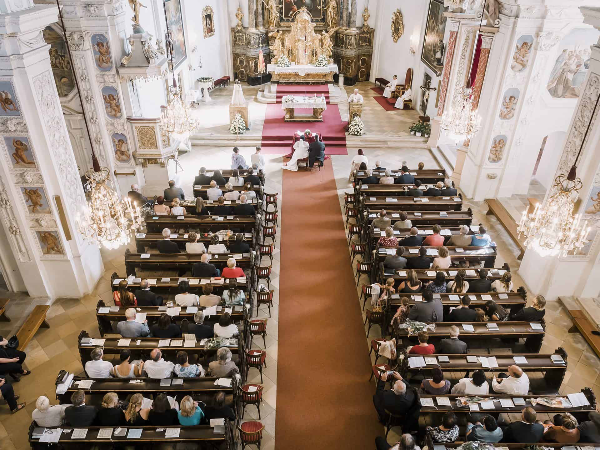 Eine Hochzeitszeremonie in einer Kirche mit Menschen, die auf den Kirchenbänken sitzen.