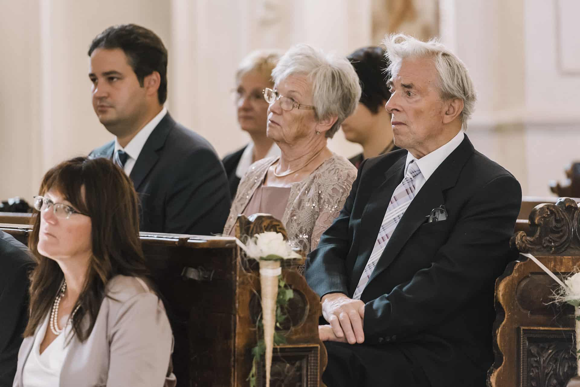Eine Gruppe von Menschen sitzt bei einer Hochzeit in Kirchenbänken.