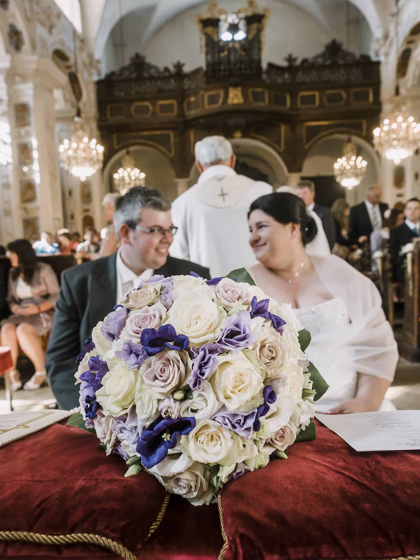Eine Braut und ein Bräutigam sitzen an einem Tisch in einer Kirche.
