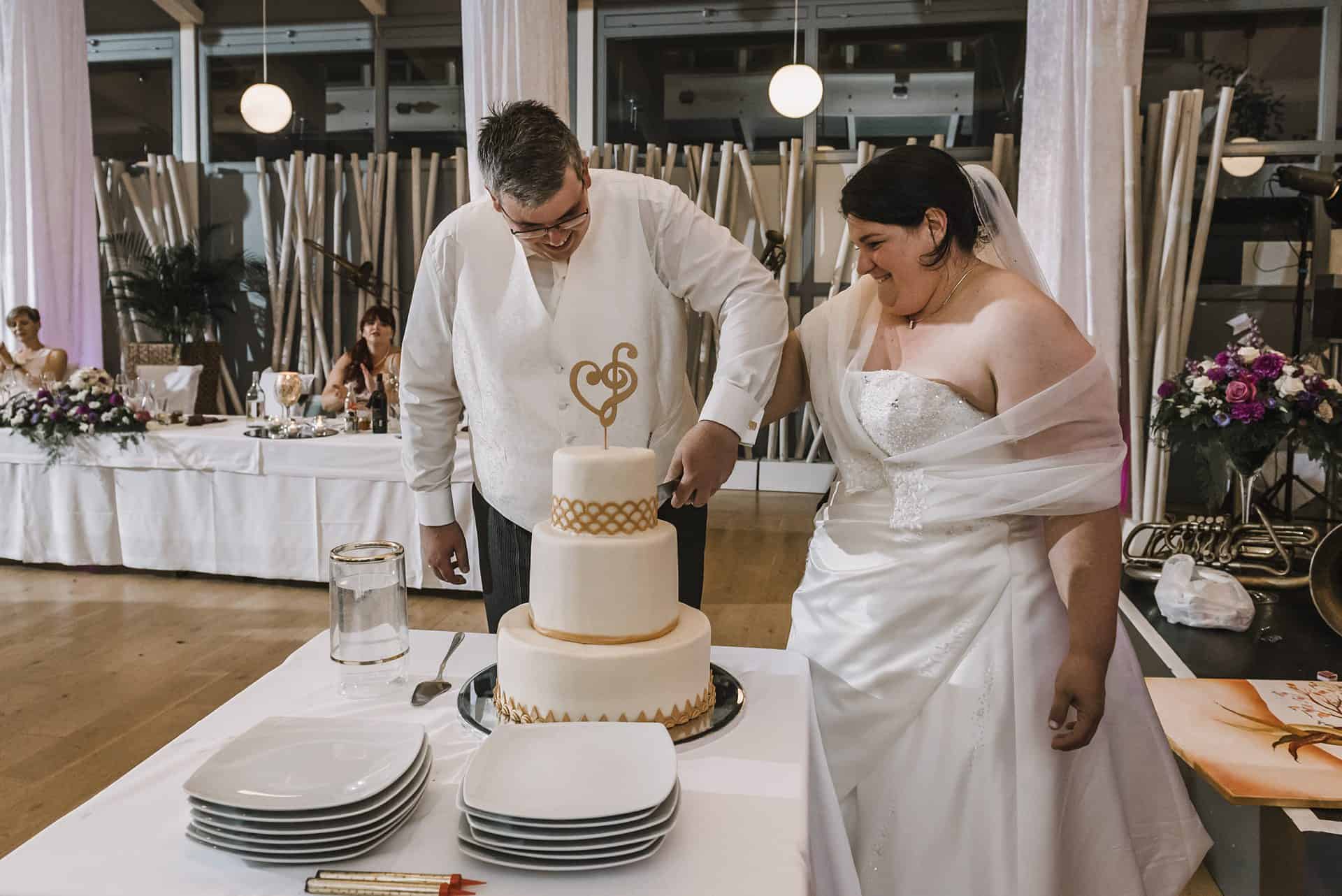 Eine Braut und ein Bräutigam schneiden ihre Hochzeitstorte an.