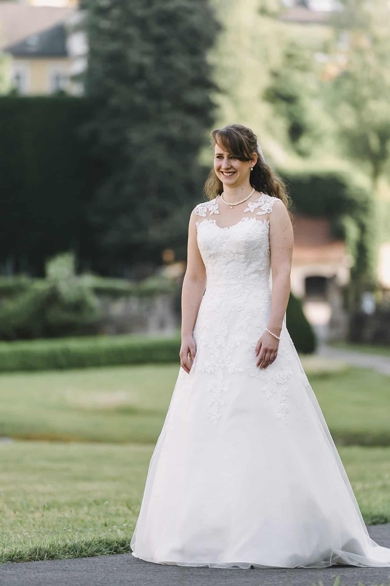 Eine Braut in einem Hochzeitskleid steht in einem Park.