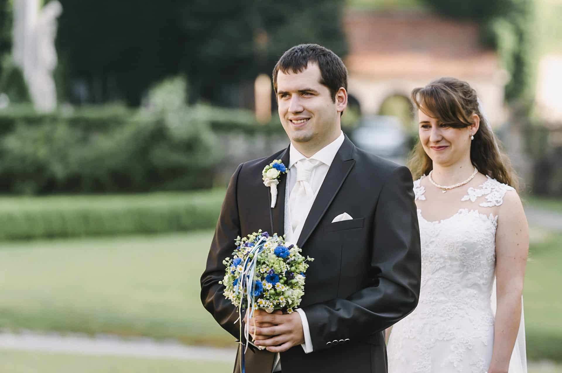 Eine Braut und ein Bräutigam stehen nebeneinander in einem Park.