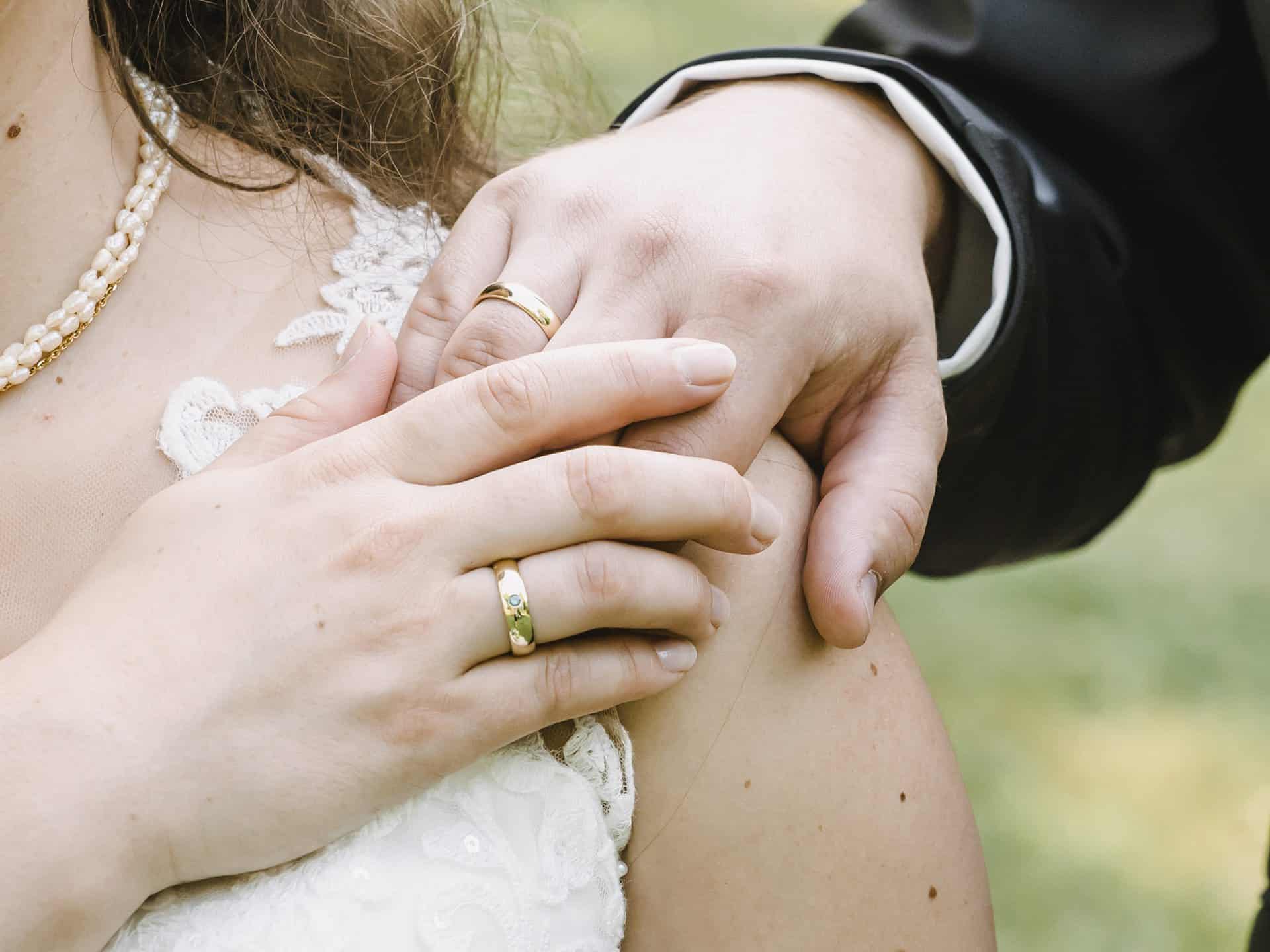 Eine Braut und ein Bräutigam halten sich gegenseitig an den Händen.