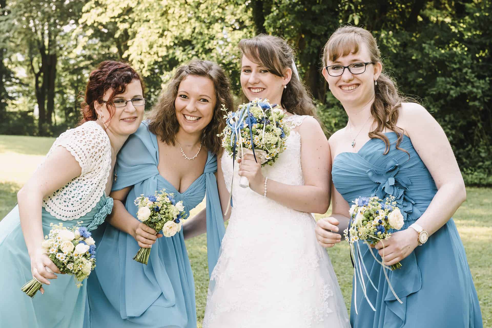Vier Brautjungfern in blauen Kleidern posieren für ein Foto.