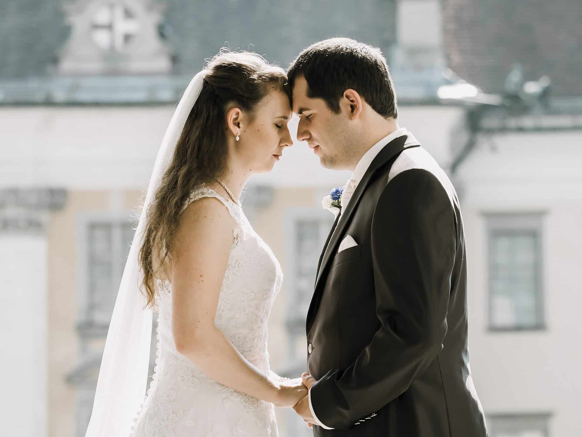 Eine Braut und ein Bräutigam schauen sich vor einem Gebäude an.