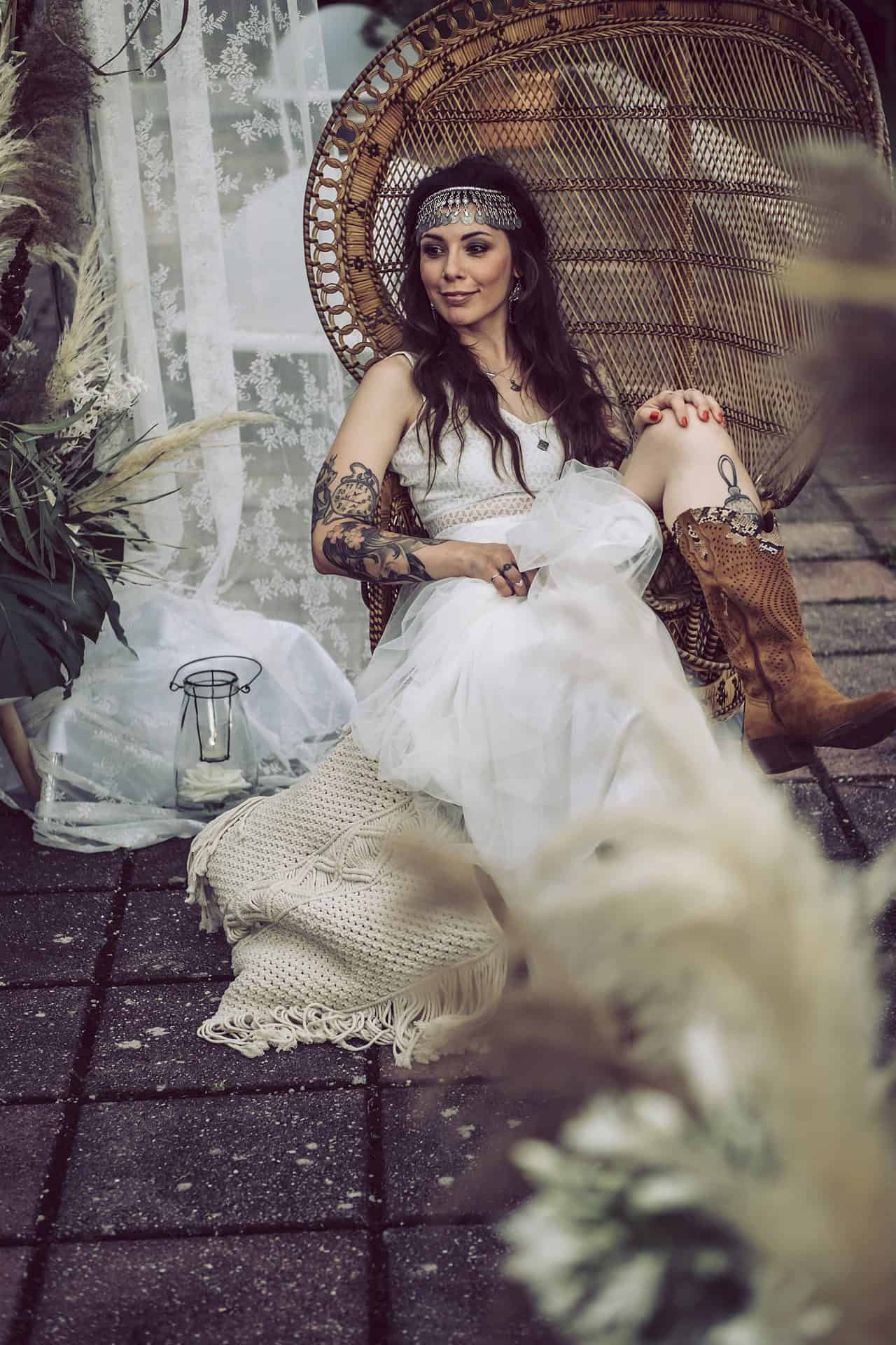 Eine Frau in einem weißen Kleid sitzt auf einem Korbstuhl.
