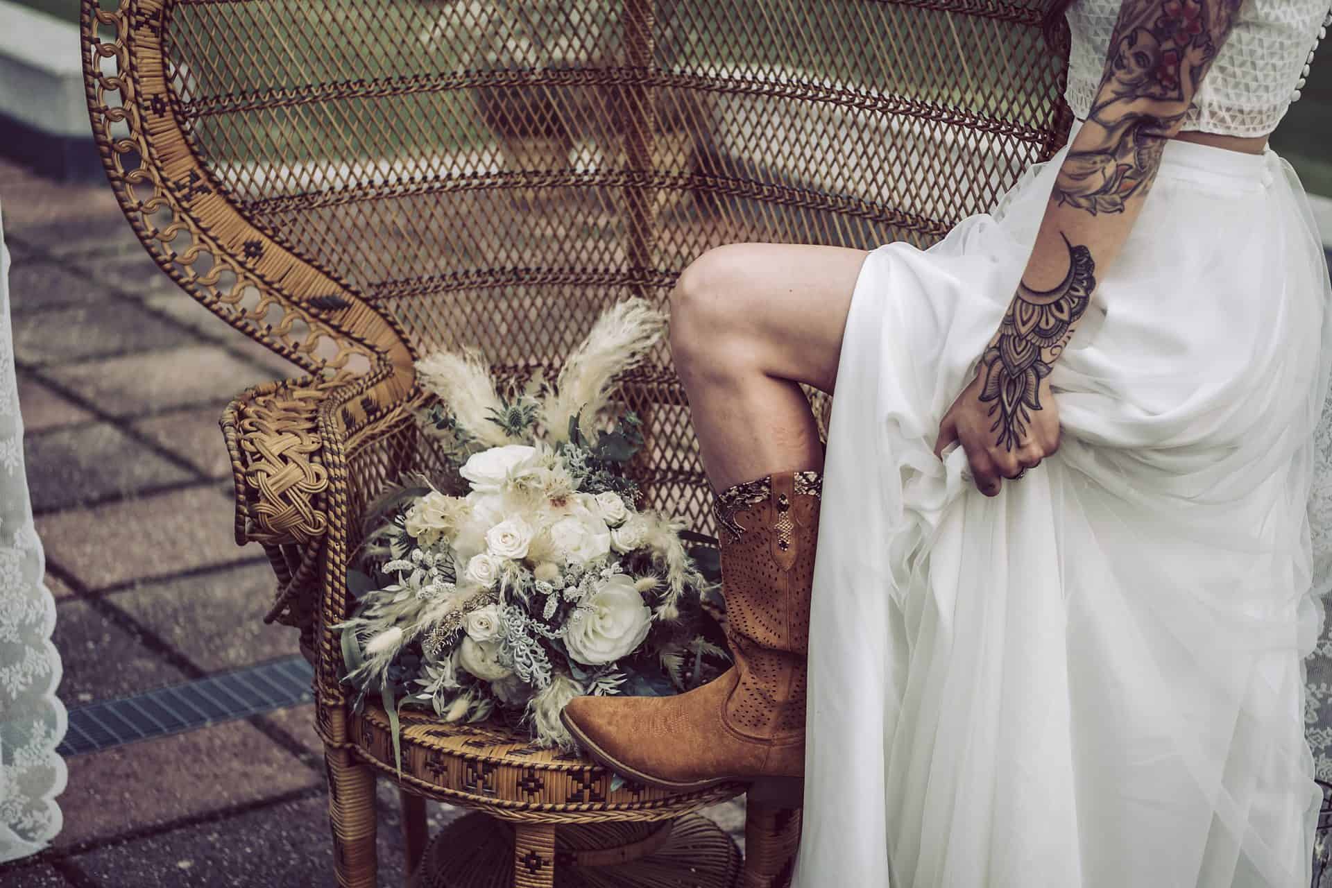 Eine Braut mit Tätowierungen sitzt auf einem Stuhl.