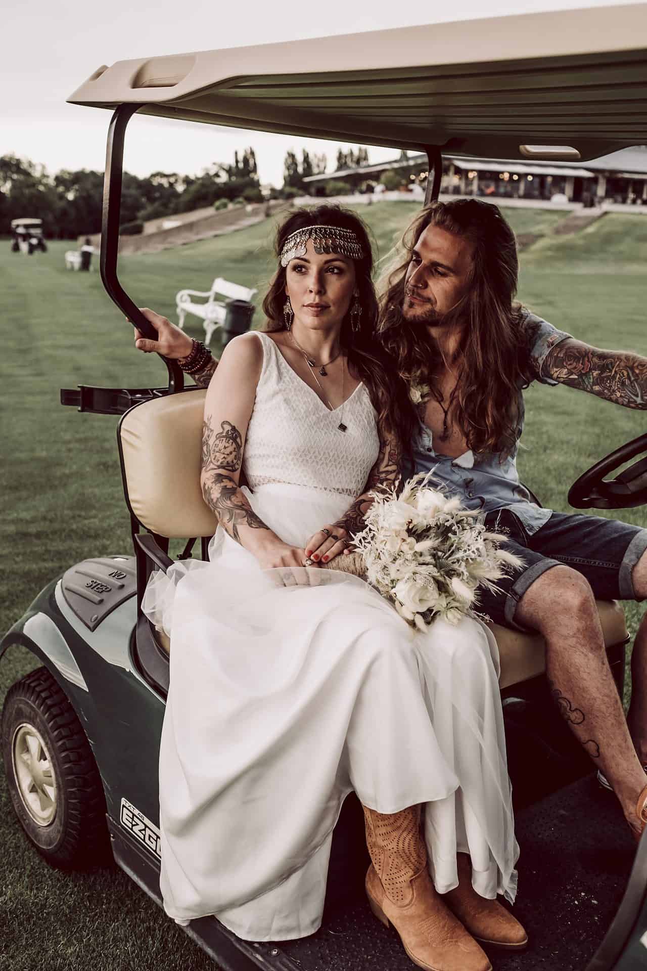 Eine Braut und ein Bräutigam sitzen in einem Golfwagen.