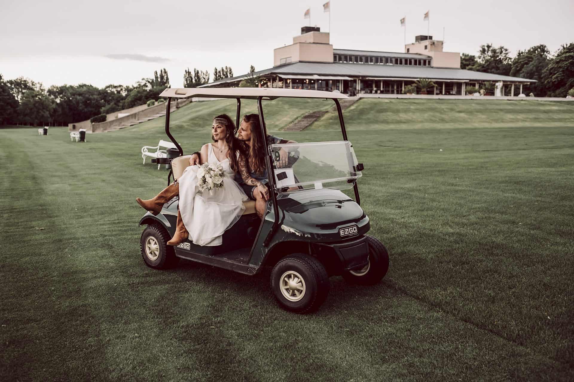 Zwei Bräute fahren in einem Golfwagen auf einem Golfplatz.
