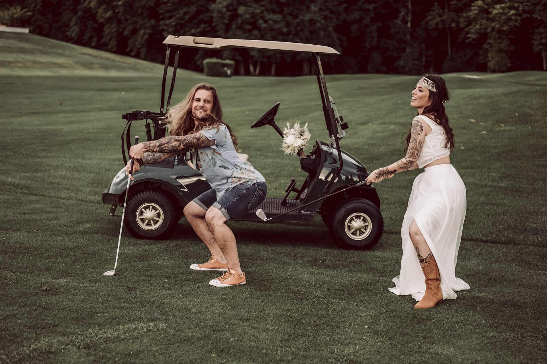 Eine Braut und ein Bräutigam posieren neben einem Golfwagen.