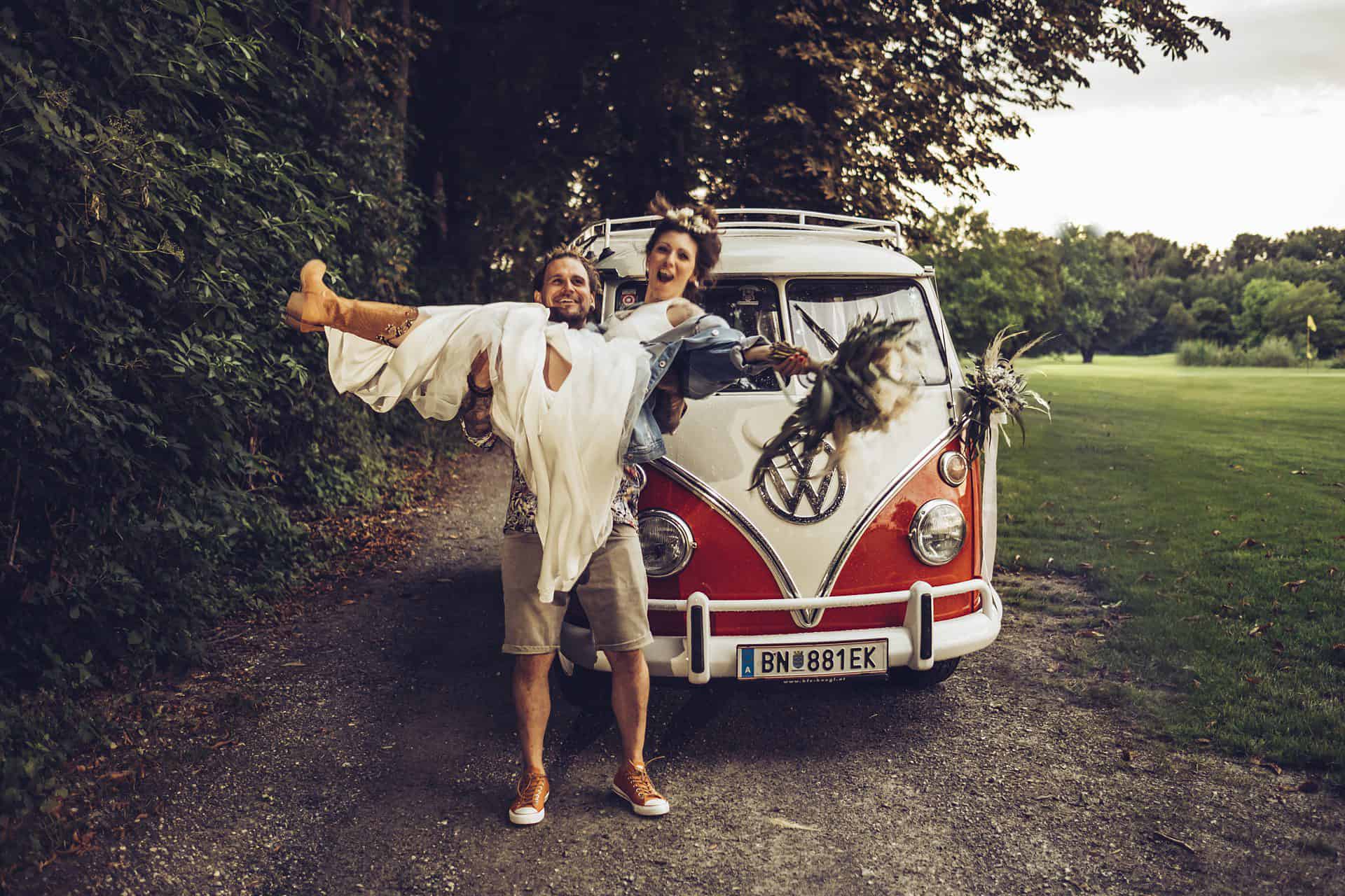 Eine Braut und ein Bräutigam stehen neben einem VW-Wohnmobil.