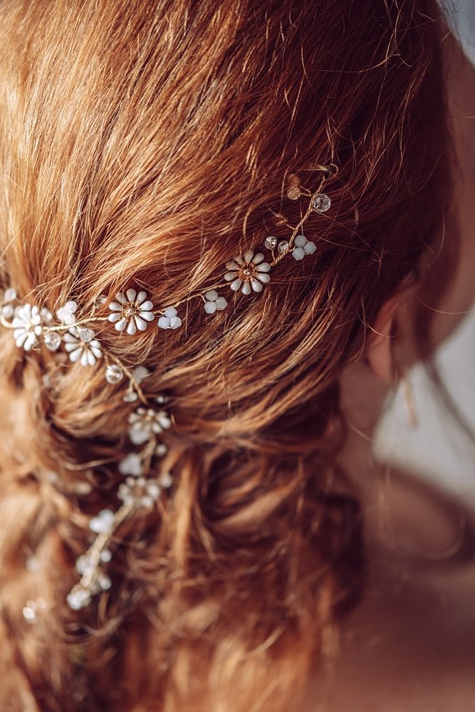 Eine Braut mit langen roten Haaren, die einen Blumenhaarkamm trägt.