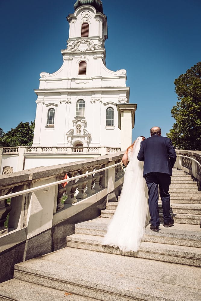 Eine Braut und ein Bräutigam gehen die Stufen einer Kirche hinunter.