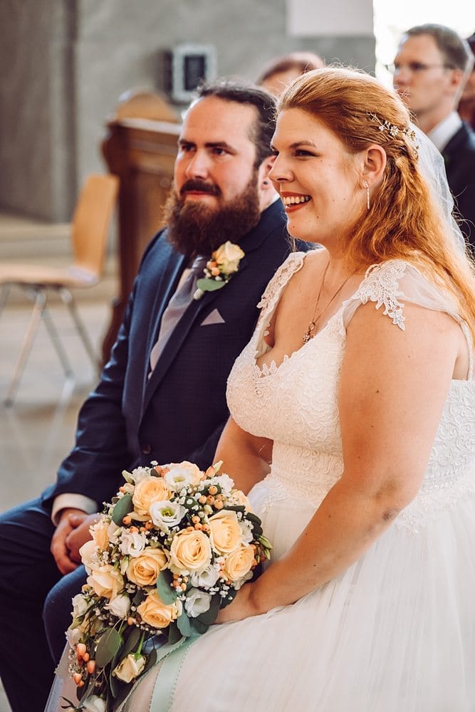 Eine Braut und ein Bräutigam lächeln sich während ihrer Hochzeitszeremonie an.