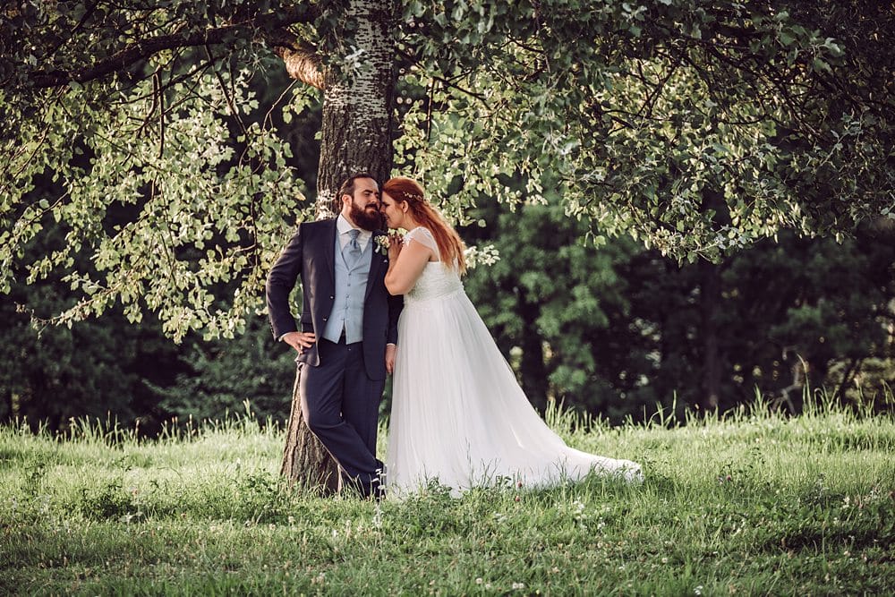 Eine Braut und ein Bräutigam posieren unter einem Baum.