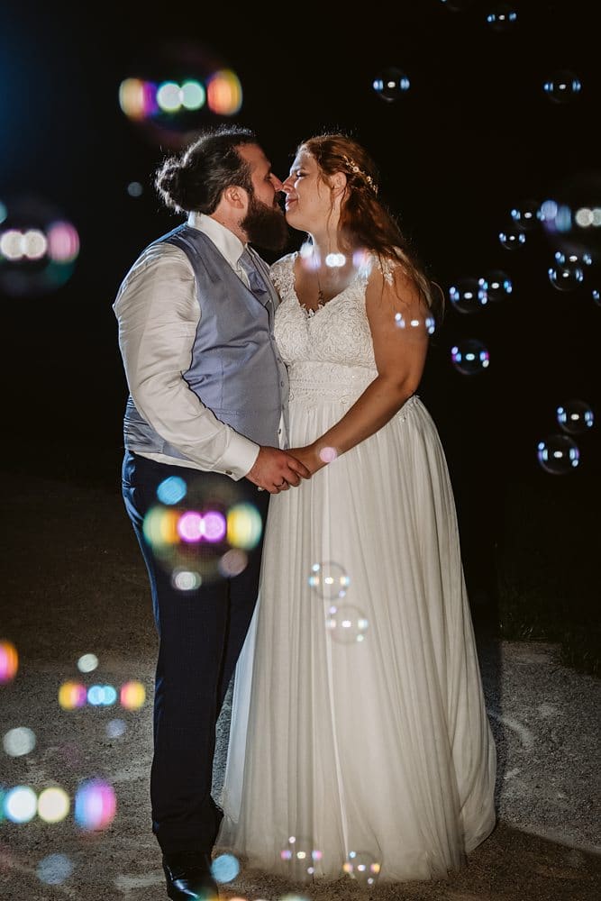 Eine Braut und ein Bräutigam küssen sich vor Seifenblasen.