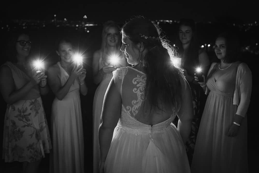Eine Braut mit ihren Brautjungfern, die nachts Kerzen halten.