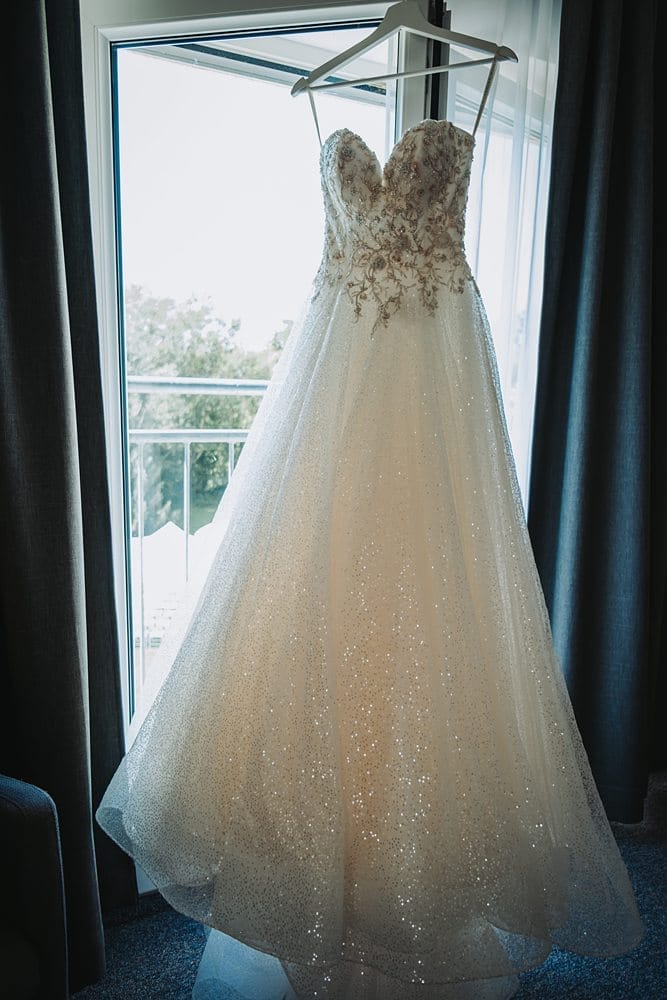 Ein Hochzeitskleid hängt vor einem Fenster.
