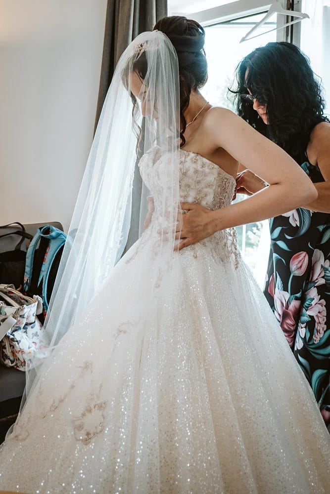 Eine Frau zieht in einem Hotelzimmer ein Hochzeitskleid an.