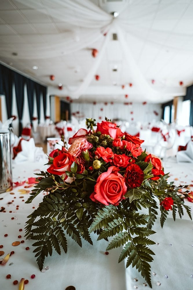 Ein Tisch mit roten Rosen und Konfetti darauf.