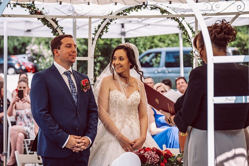 Eine Braut und ein Bräutigam stehen während ihrer Hochzeitszeremonie unter einem Pavillon.