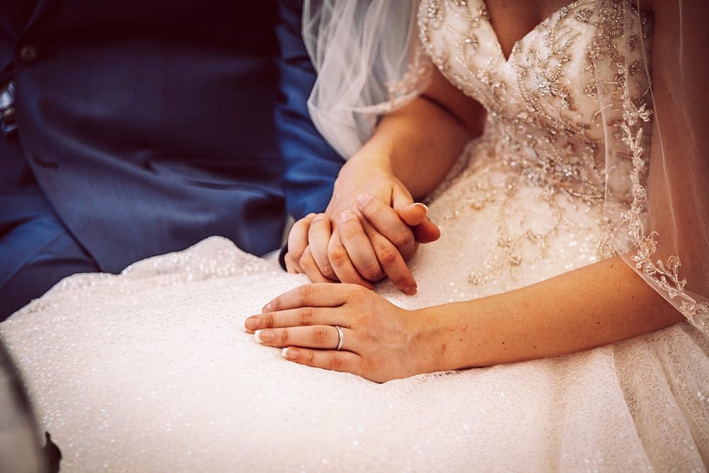Eine Braut und ein Bräutigam halten sich an ihrem Hochzeitstag an den Händen.