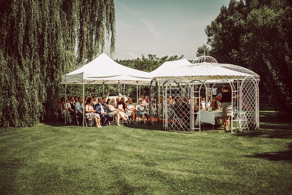Eine Hochzeitszeremonie unter einem Pavillon in einem Garten.