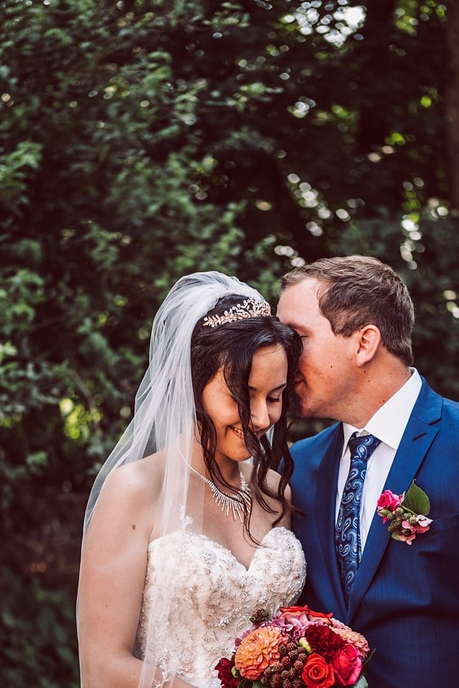 Eine Braut und ein Bräutigam küssen sich im Wald.