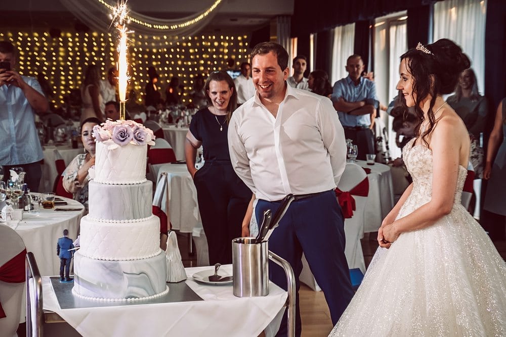 Eine Braut und ein Bräutigam schneiden ihre Hochzeitstorte mit Wunderkerzen an.