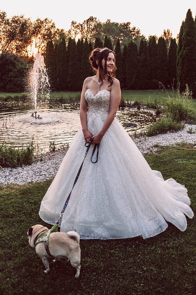 Eine Braut im Hochzeitskleid mit einem Hund an der Leine.