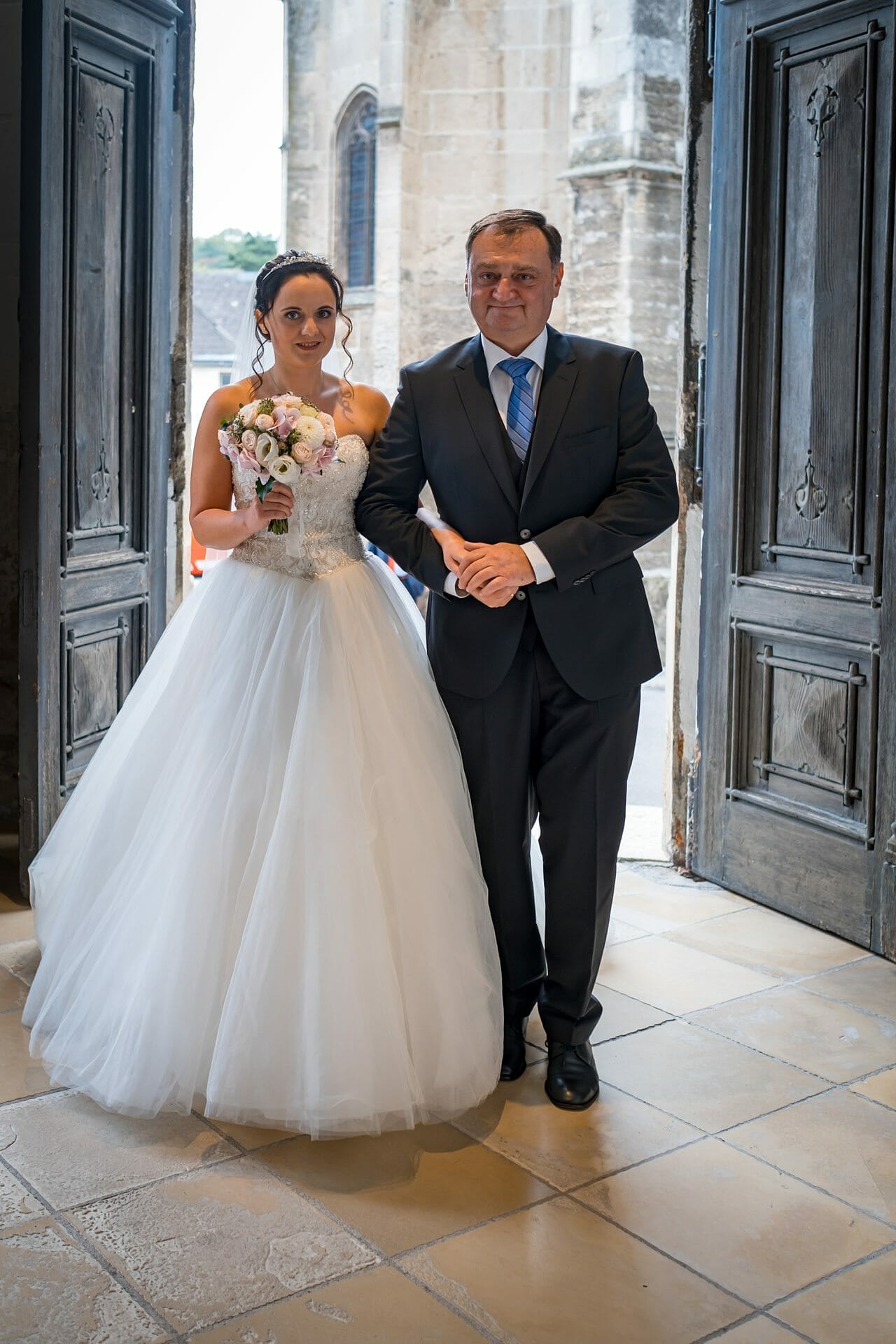 Eine Braut und ihr Vater stehen im Eingang einer Kirche.