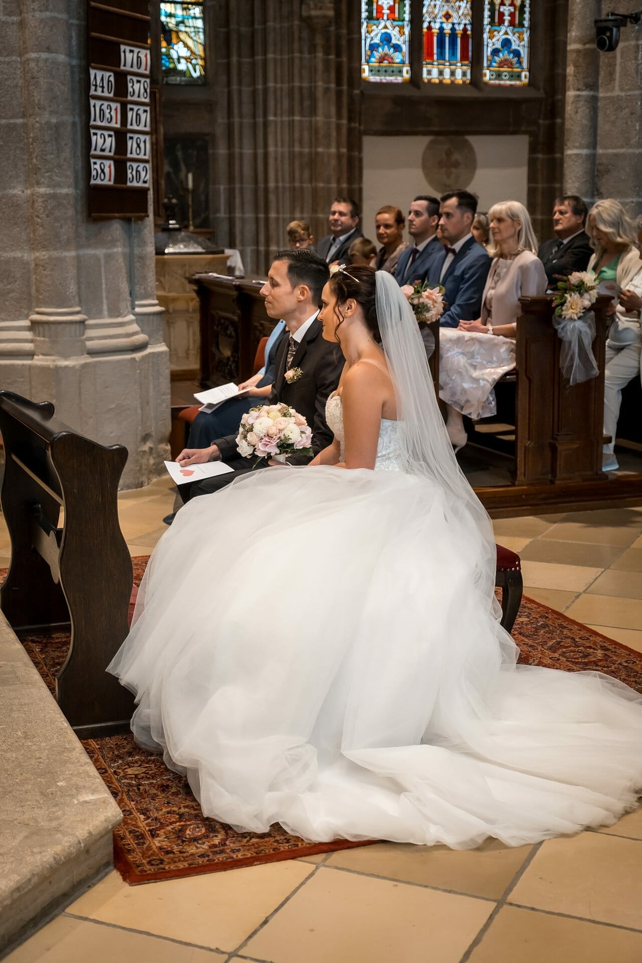 Eine Braut und ein Bräutigam sitzen während ihrer Hochzeitszeremonie in einer Kirche.