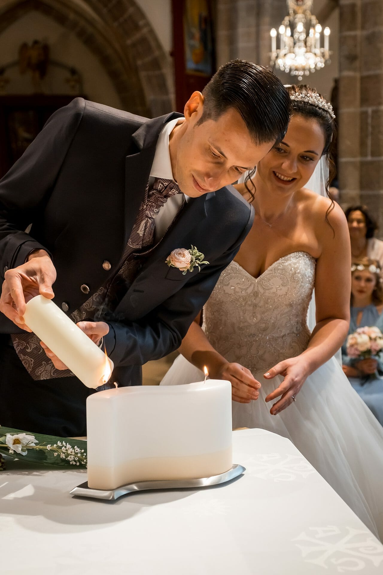 Eine Braut und ein Bräutigam zünden in einer Kirche eine Kerze an.