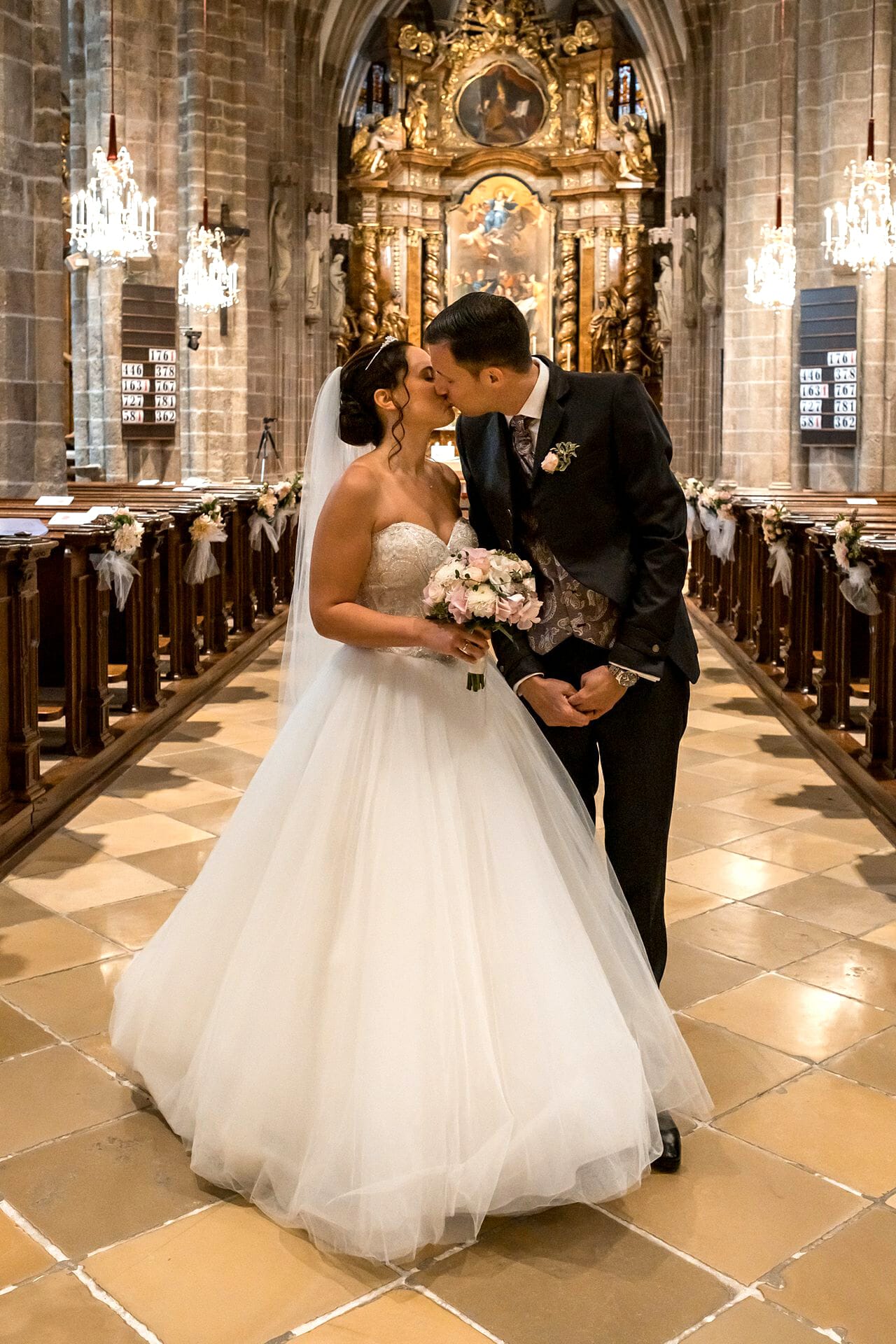 Eine Braut und ein Bräutigam küssen sich in einer Kirche.