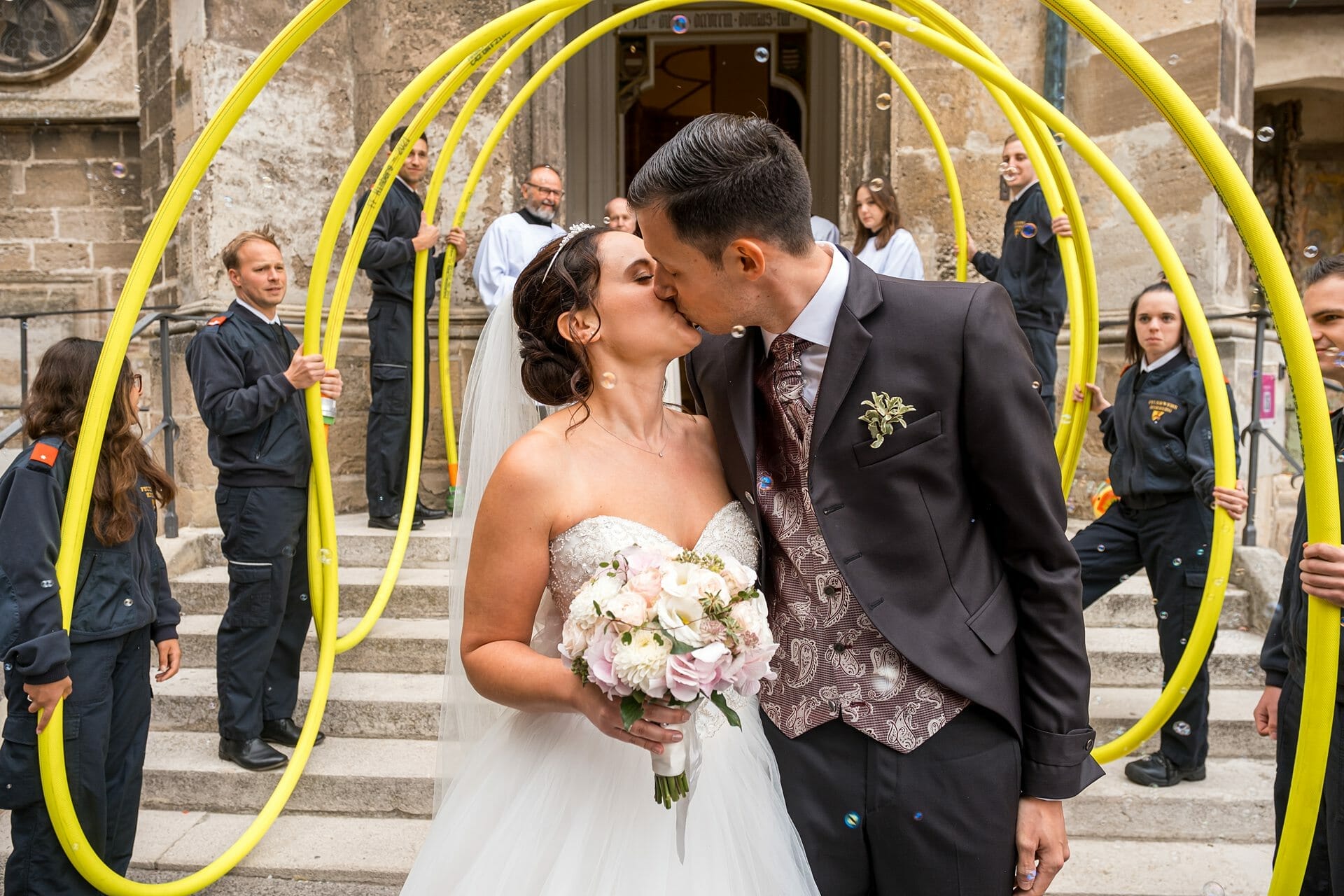 Eine Braut und ein Bräutigam küssen sich vor einem gelben Reifen.