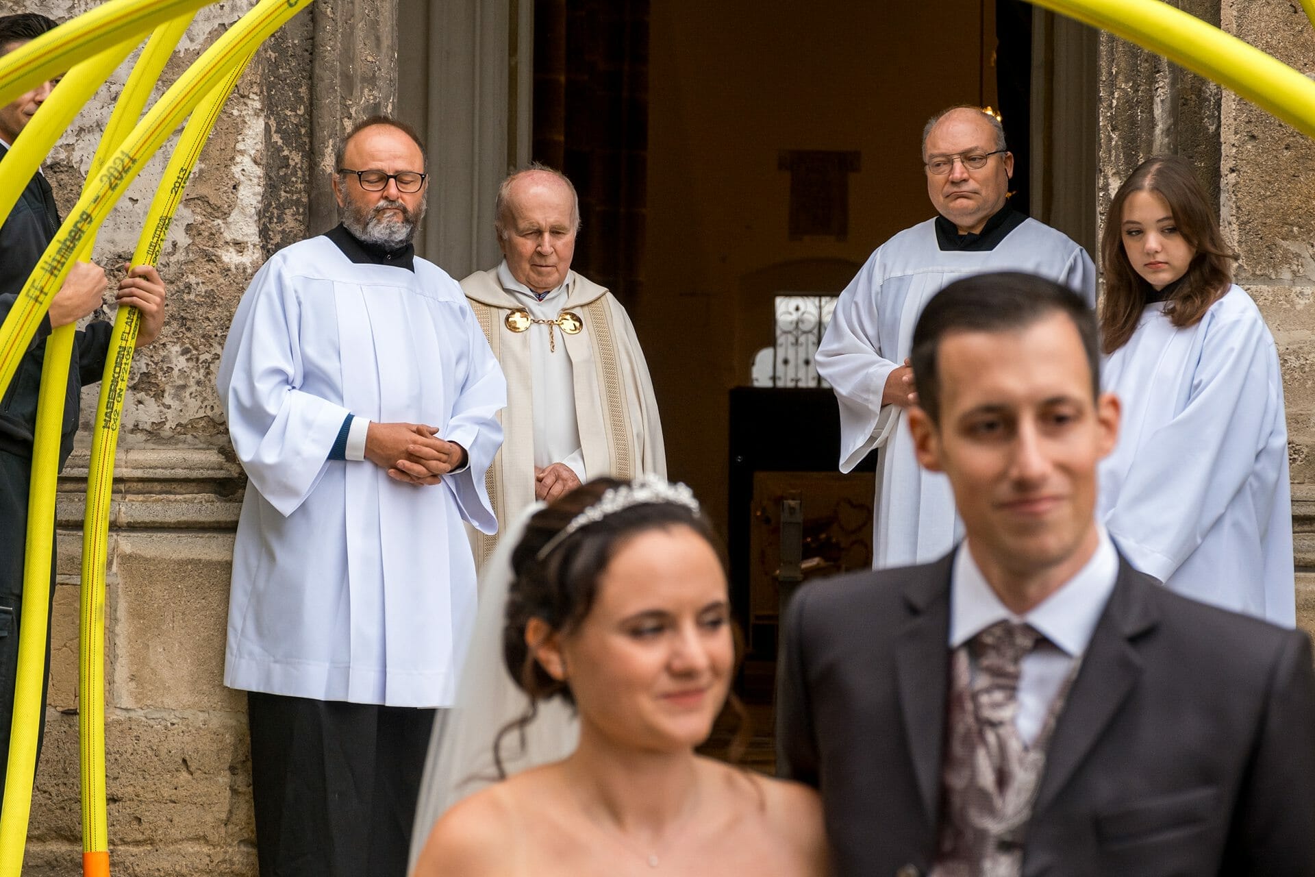 Eine Braut und ein Bräutigam stehen vor einem gelben Bogen.