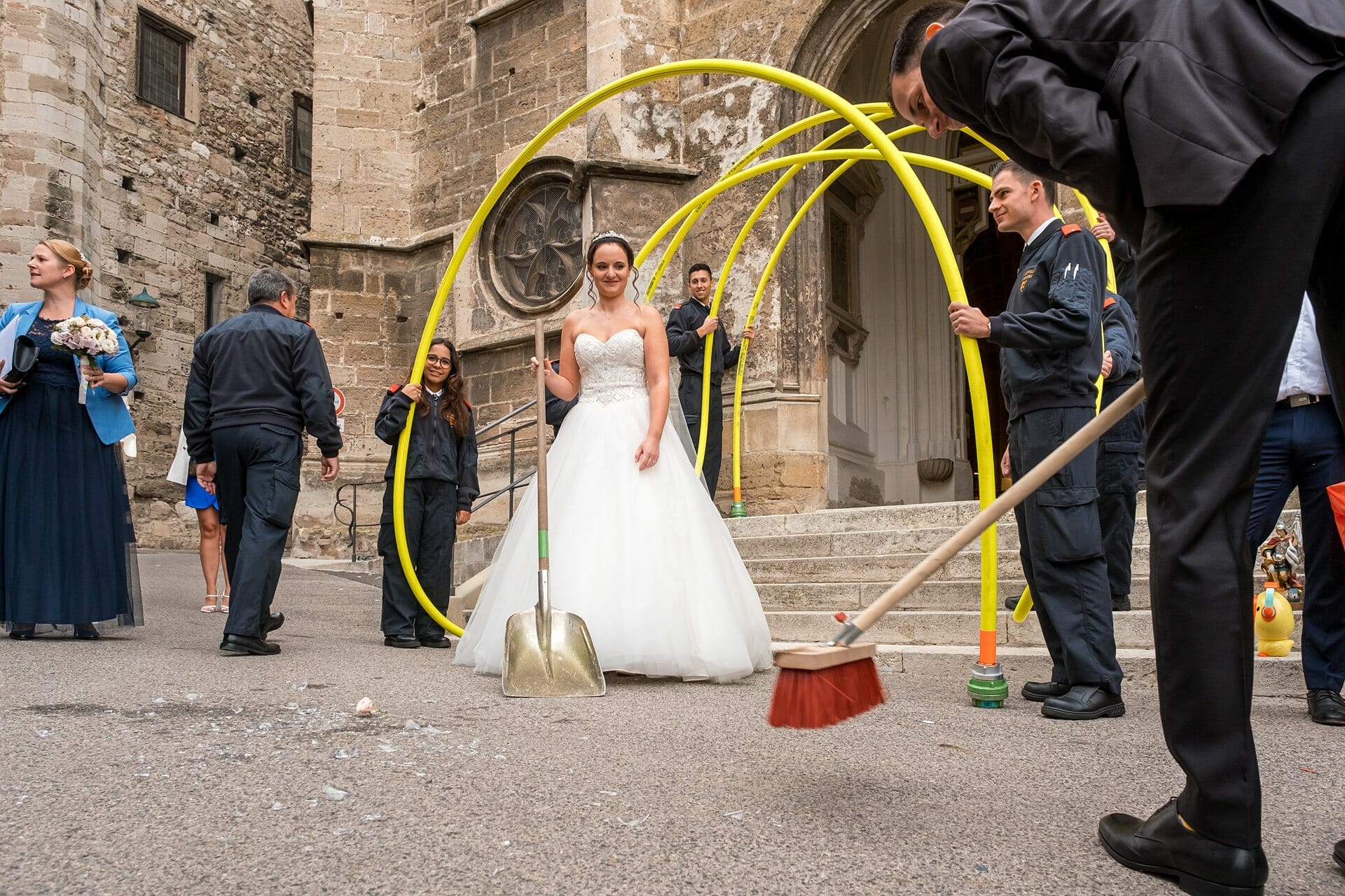 Ein Brautpaar mit einem Besen vor einer Kirche.