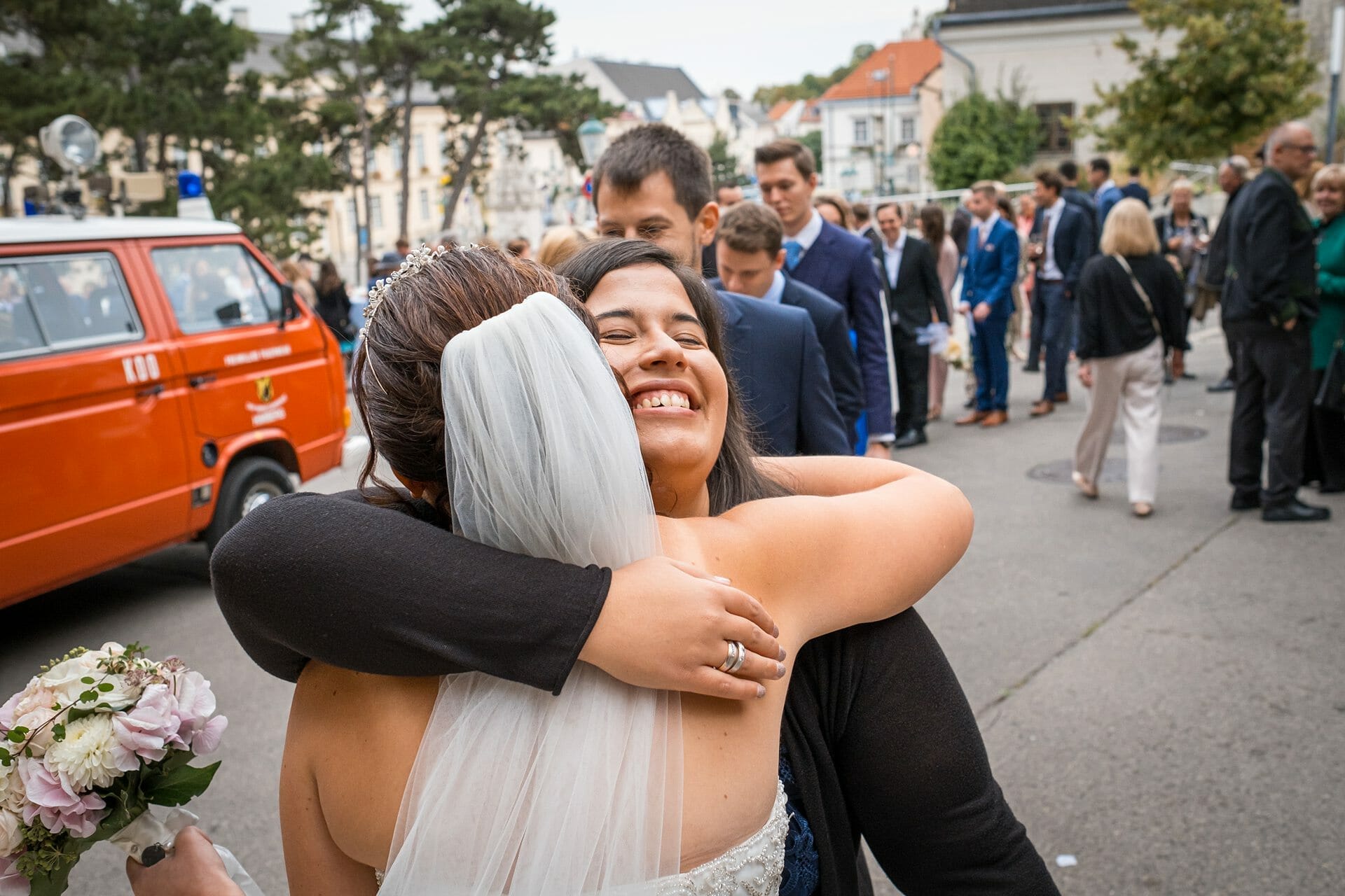 Eine Braut umarmt ihre Mutter vor einer Menschenmenge.