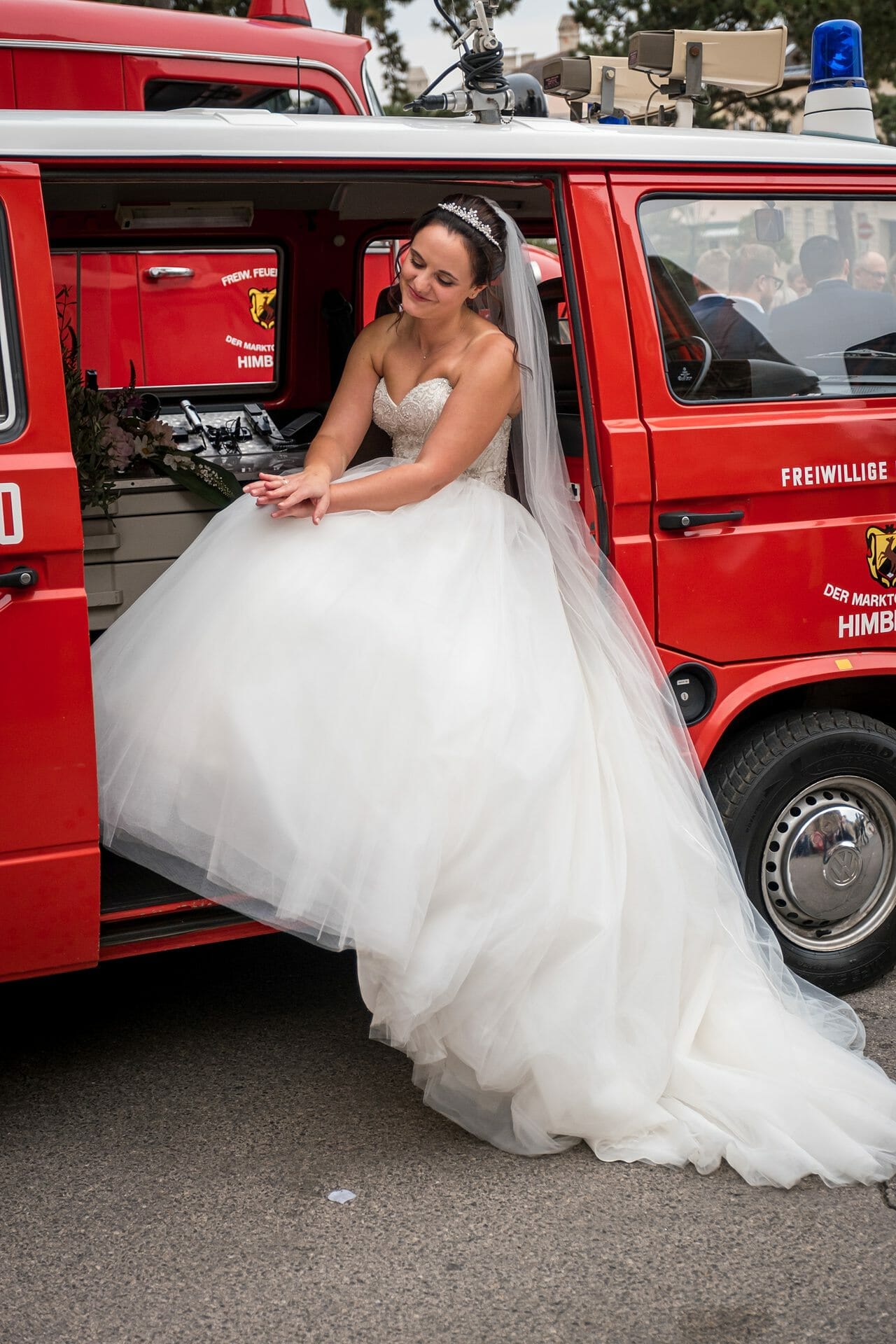 Eine Braut sitzt hinten in einem VW-Bus.