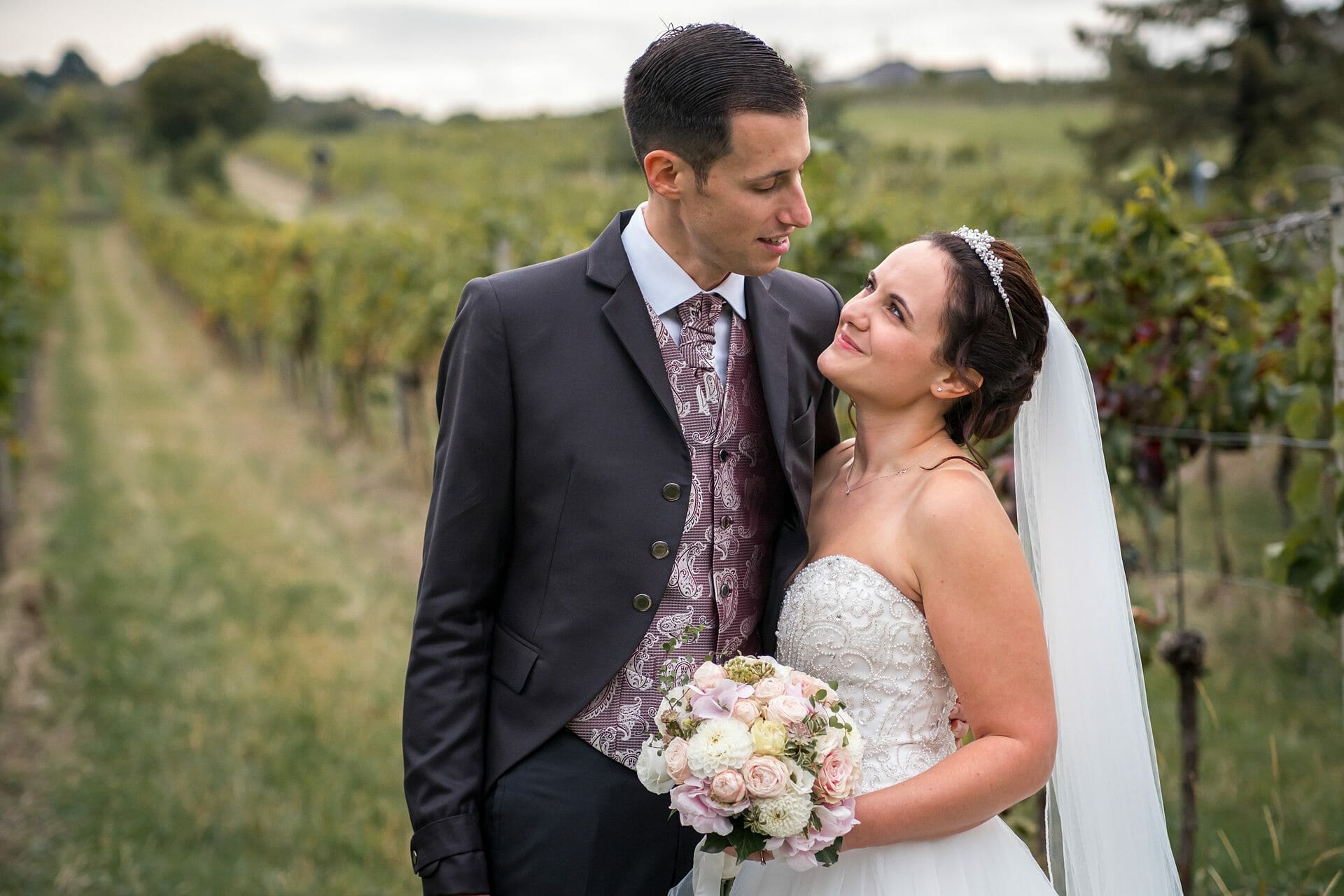 Eine Braut und ein Bräutigam stehen in einem Weinberg.