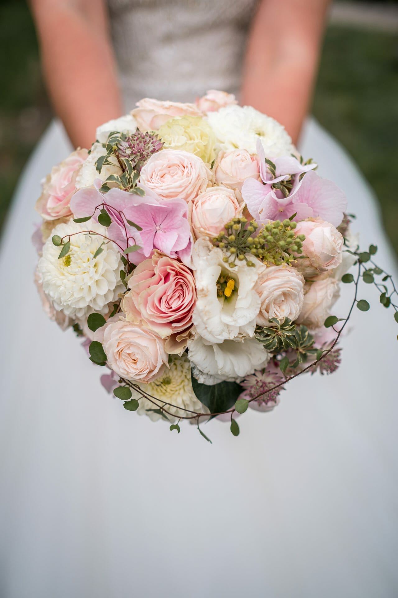 Eine Braut hält einen Strauß rosa und weißer Blumen.