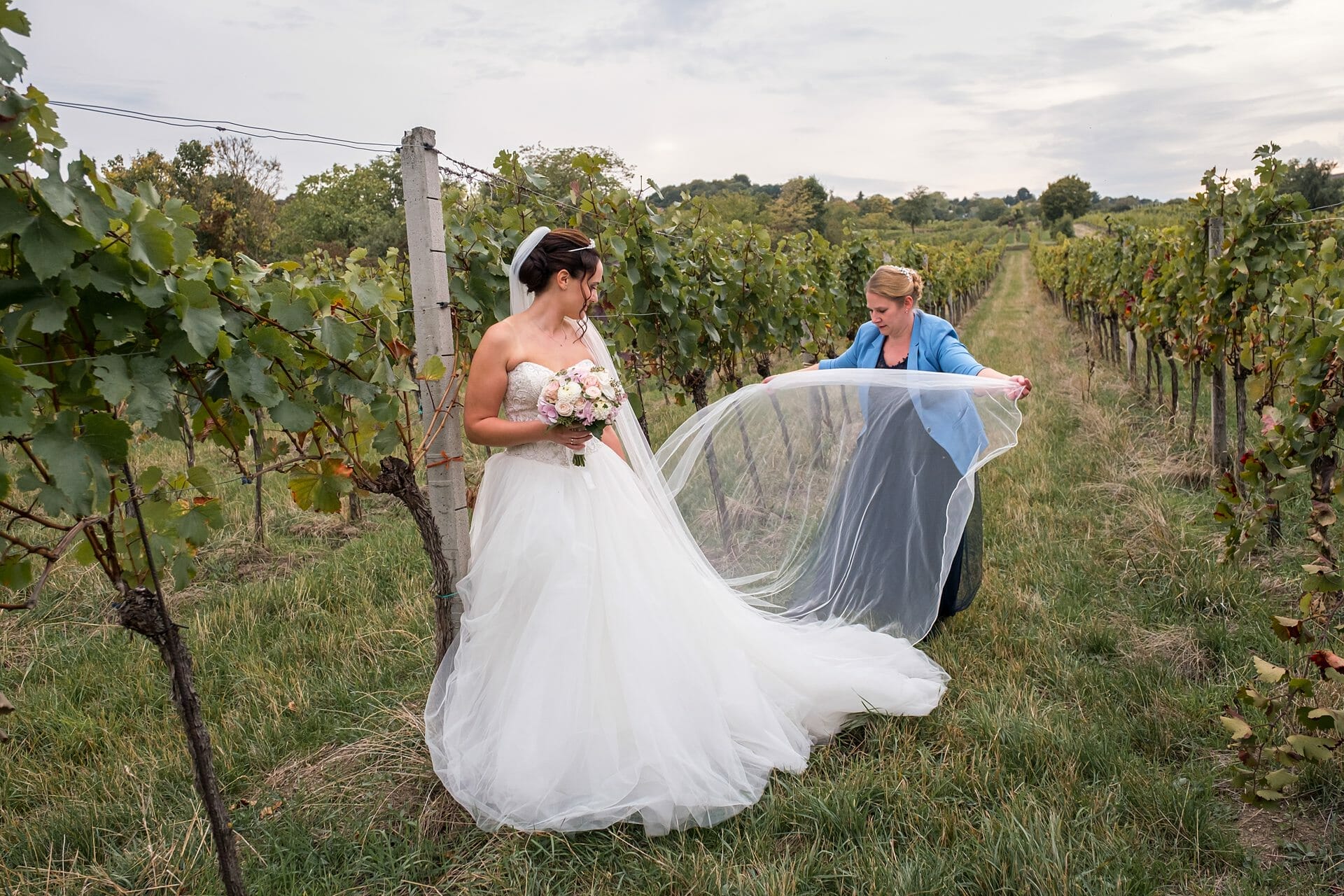Eine Braut in einem Weinberg, die ihren Schleier hält.