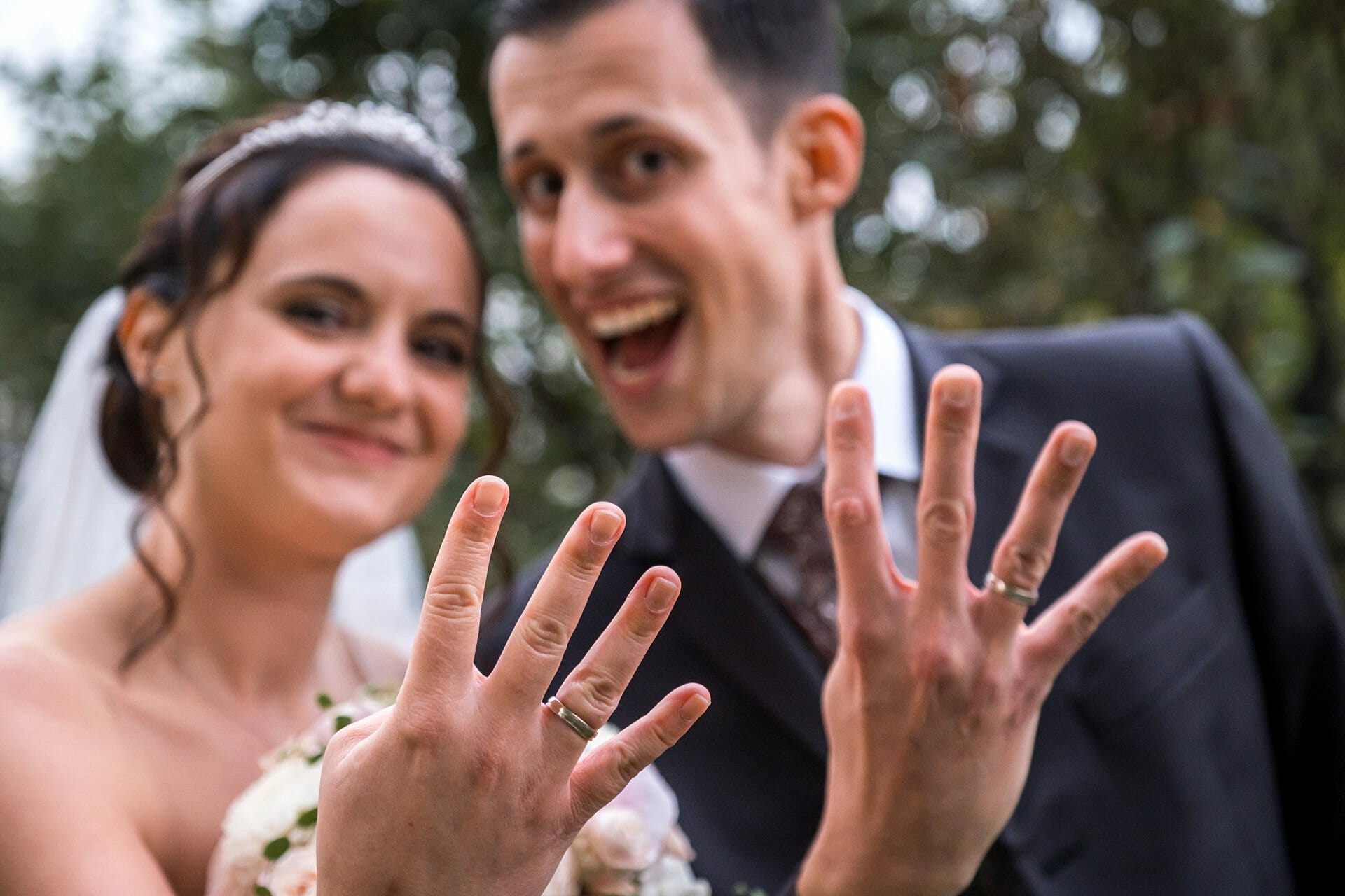 Eine Braut und ein Bräutigam zeigen ihre Eheringe.